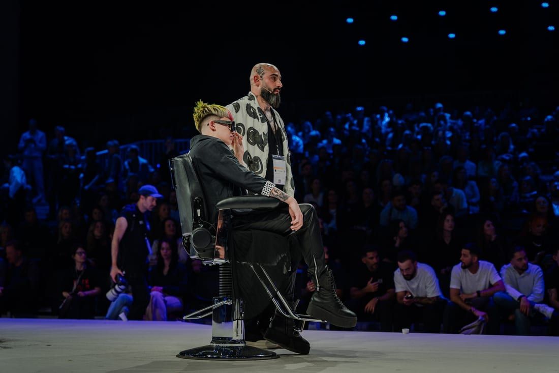 Liviu Manolache pe scenă, în fața publicului, la o competiție de barbering