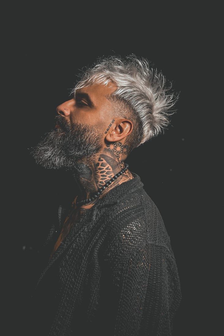 Bărbat cu păr argintiu și barbă, portret din profil cu tatuaje
