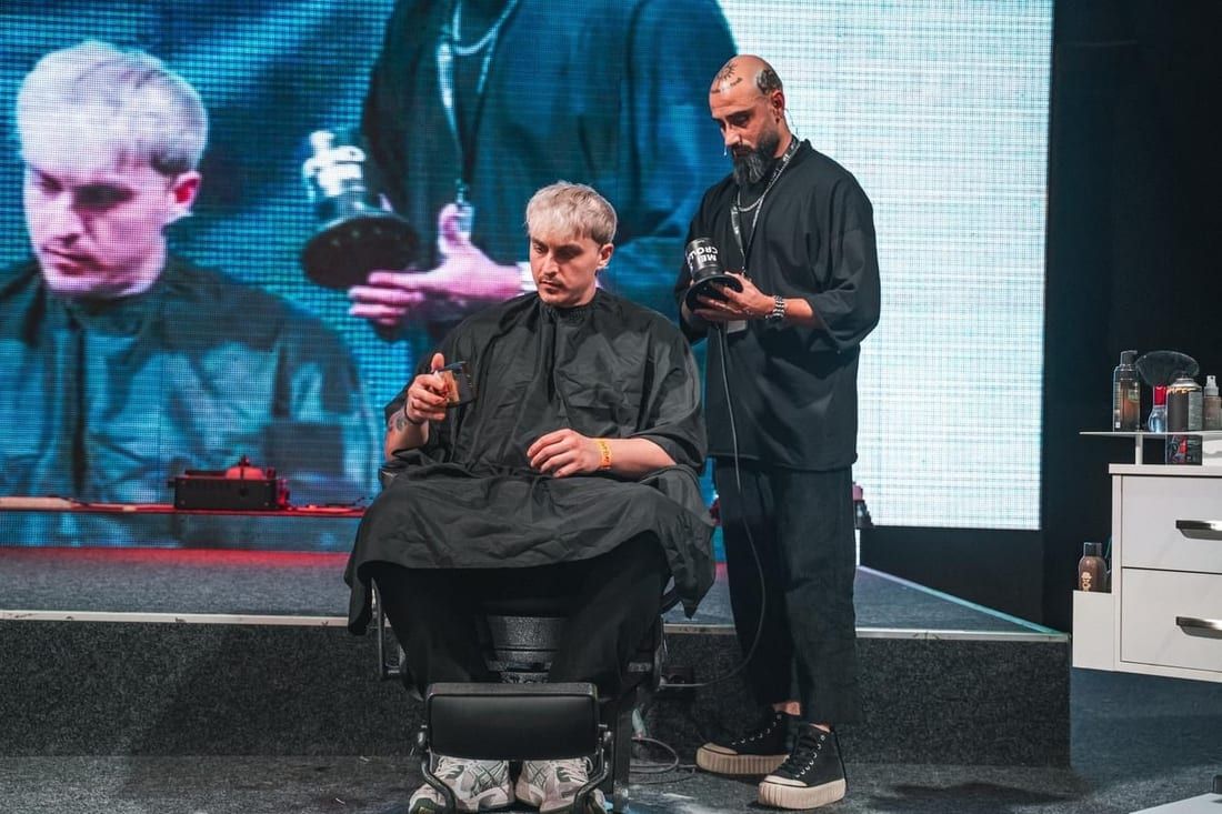 Demonstrație de tuns pe scenă, cu ecran de proiecție în fundal